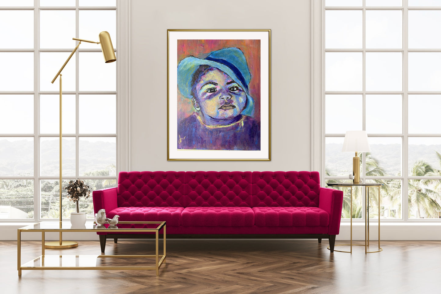 Baby boy in blue hat in colours purple, pink and  blue in gold frame. In room with bright pink sofa with gold toned furniture